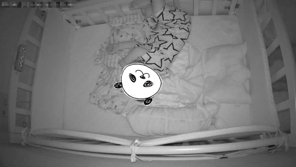 ベビーベッドに寝転ぶ赤ちゃん、モノクロ